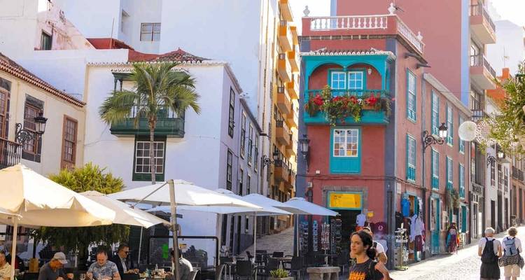 Scène de rue avec des bâtiments colorés et des cafés en terrasse.