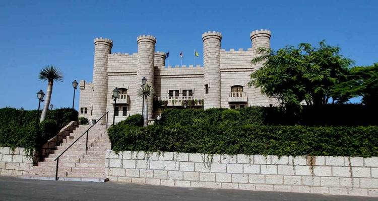 Un bâtiment semblable à un château avec des drapeaux au sommet d'un mur de pierre.