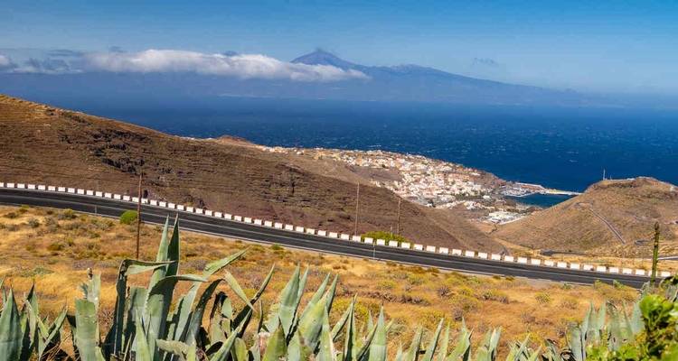 Vista panorámica de un pueblo costero y un volcán al fondo.