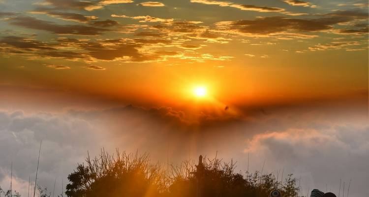 Malerischer Sonnenaufgang über einem Wolkenmeer, mit lebendigen Farben am Himmel.