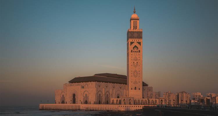Una gran mezquita junto al océano durante el atardecer.