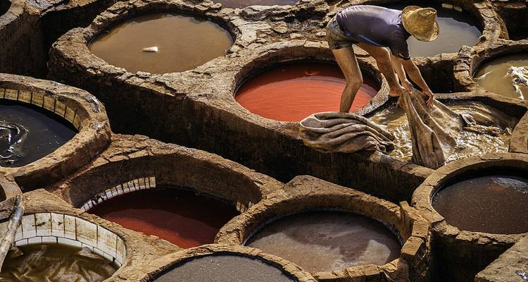 Un trabajador en una tenería tradicional con grandes cubas de tinte.