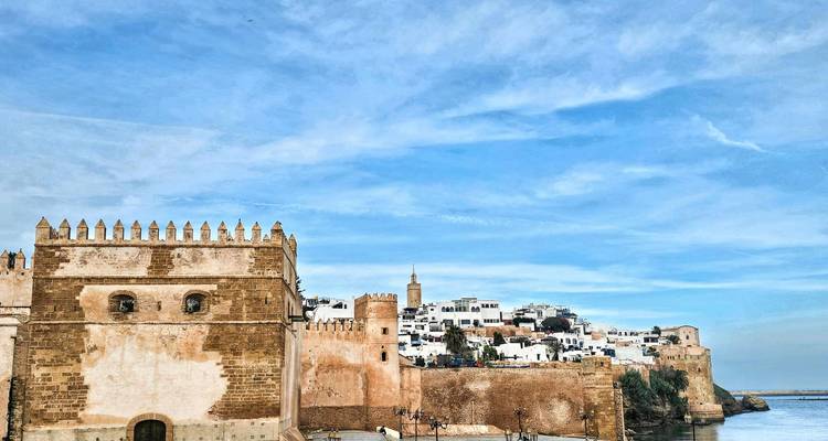 Historische Mauern der Kasbah am Flussufer von Rabat vor einem klaren blauen Himmel und Gewässer.