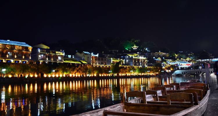 Traditionelle chinesische Gebäude, die nachts an einem Fluss beleuchtet sind.