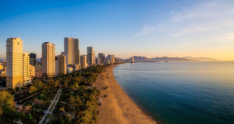 Panoramisch strandgezicht met skyline van hoogbouw langs een gouden kust.