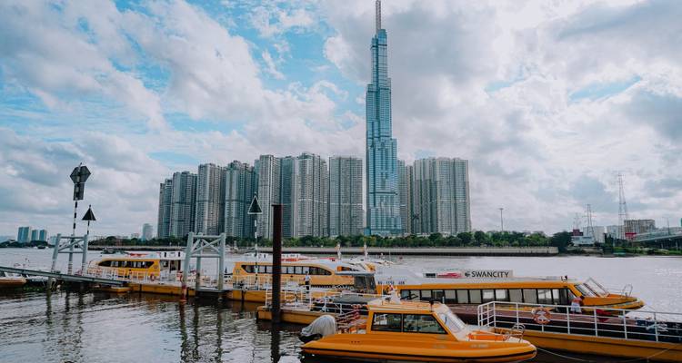 Een skyline met hoogbouw en gele boten op een rivier.
