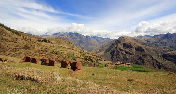 Heuvelachtig landschap met oude ruïnes en blauwe luchten.
