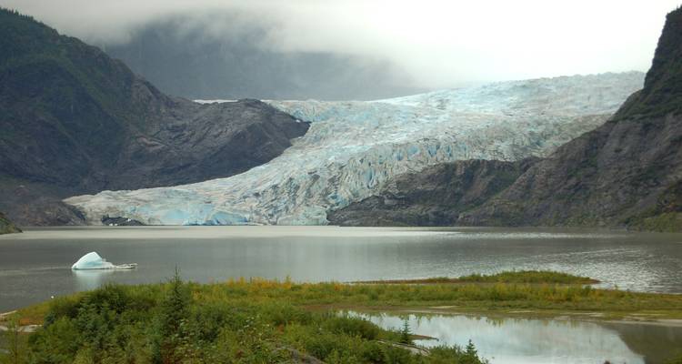 Glacier with a lake and misty mountains.