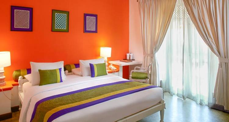 Buntes Hotelzimmer mit gestreifter Bettwäsche.