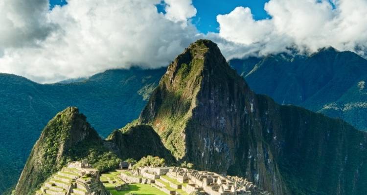 Machu Picchu met omringende mistige bergen en dramatische wolken.