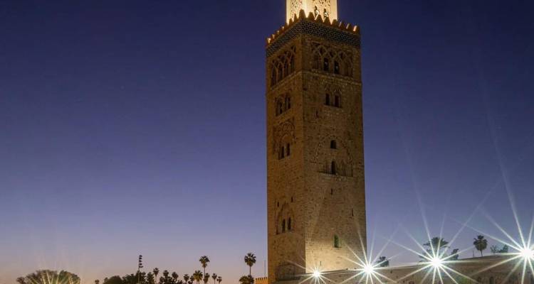 Verlichte Koutoubia-moskeetoren tegen een nachtelijke hemel.