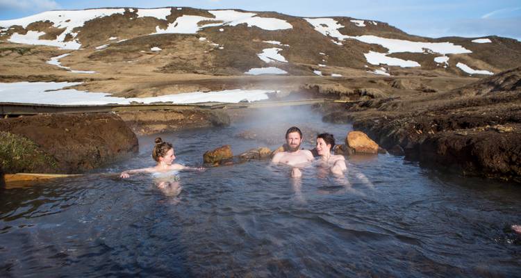 Grupo de personas disfrutando de una fuente termal natural en un paisaje nevado.