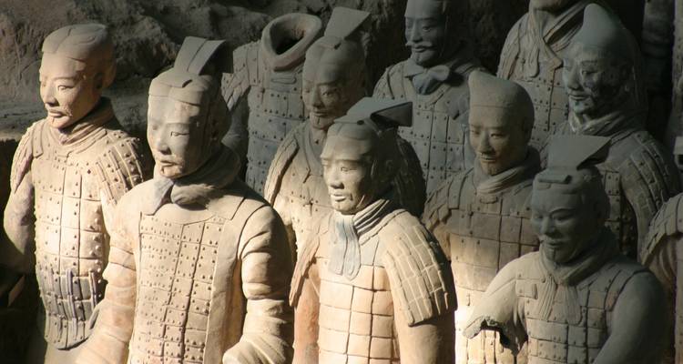 Terracotta Warriors statues in formation, partially illuminated by natural light.