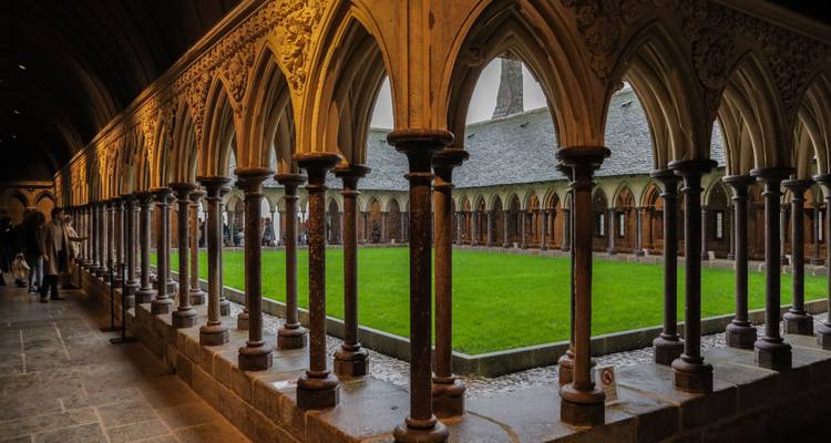 Binnenkloster met gotische bogen en groene binnenplaats.