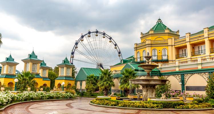 Amusement park with Ferris wheel and colorful buildings.