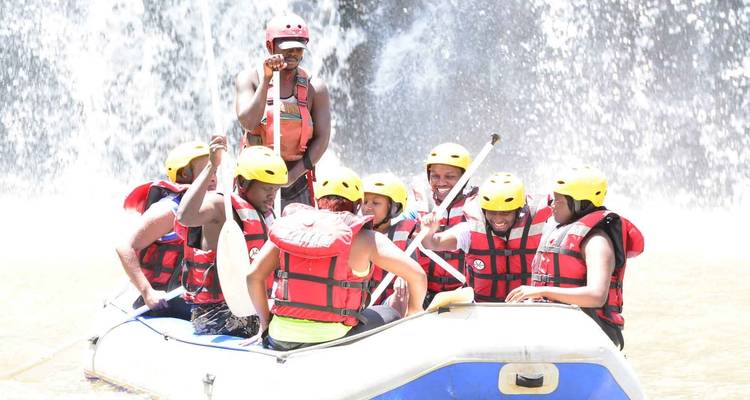 Gruppe von Wildwasserfahrern mit Helmen und Schwimmwesten, die durch Stromschnellen navigieren.