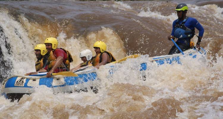 Floß mit Menschen, das einen Wasserfall in tosenden Stromschnellen hinunterfährt.