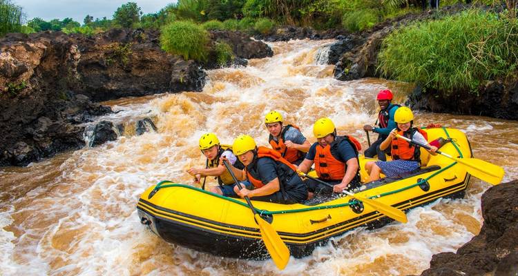Gruppe von Menschen beim Wildwasser-Rafting durch felsige Stromschnellen.