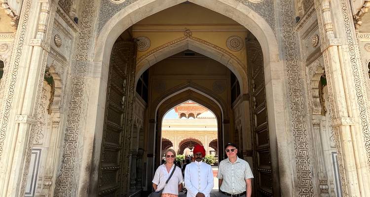 Tres personas paradas en una entrada ornamentada con arcos.