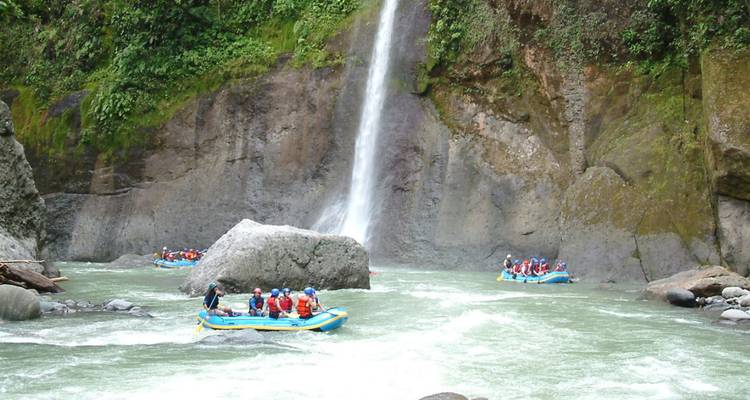 Radeaux naviguant sur une rivière avec une cascade en arrière-plan.