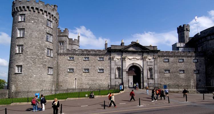 Une entrée de château avec plusieurs personnes qui se promènent.