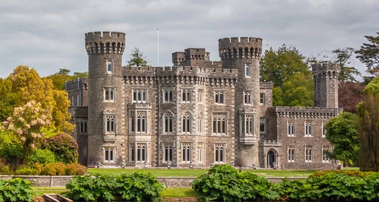Un grand château de pierre entouré de verdure.