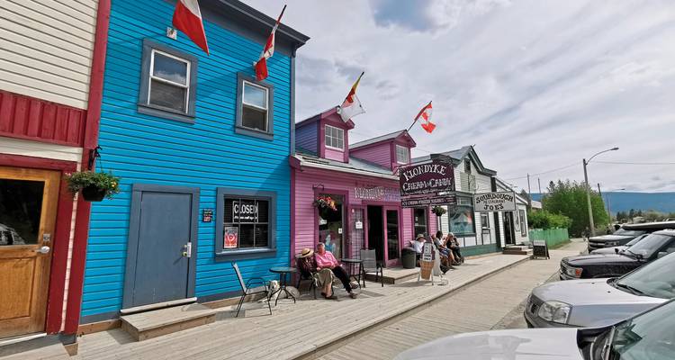Eine malerische, bunte Straße mit Geschäften und Menschen in einer kleinen Stadt.