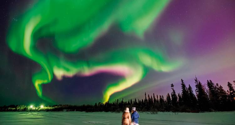 Un spectacle époustouflant d'aurores boréales au-dessus d'un terrain enneigé.