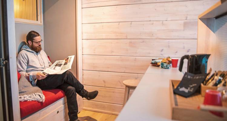 Une personne lisant à l'intérieur d'un intérieur en bois moderne et minimaliste.