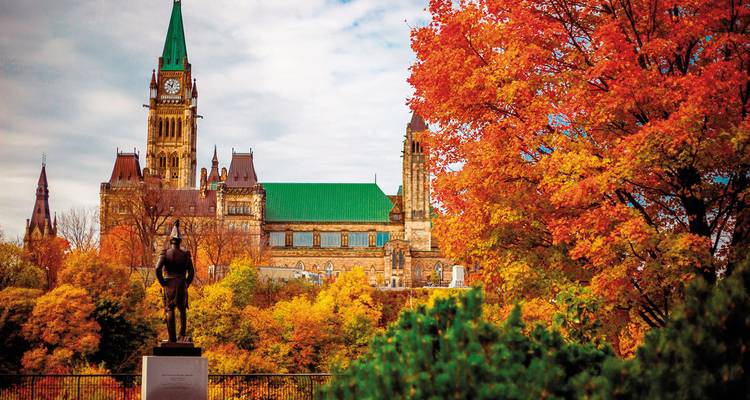 Vue des édifices du Parlement à Ottawa entourés d'un feuillage d'automne éclatant.