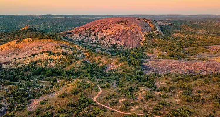 Vue du coucher de soleil sur Enchanted Rock, un grand dôme de granit rose.