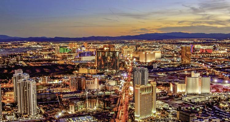 Vue aérienne d'une ville avec de nombreux bâtiments illuminés au crépuscule.