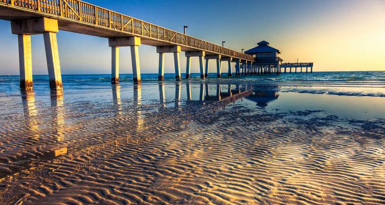 Pier bei Sonnenuntergang mit Spiegelungen im Wasser.