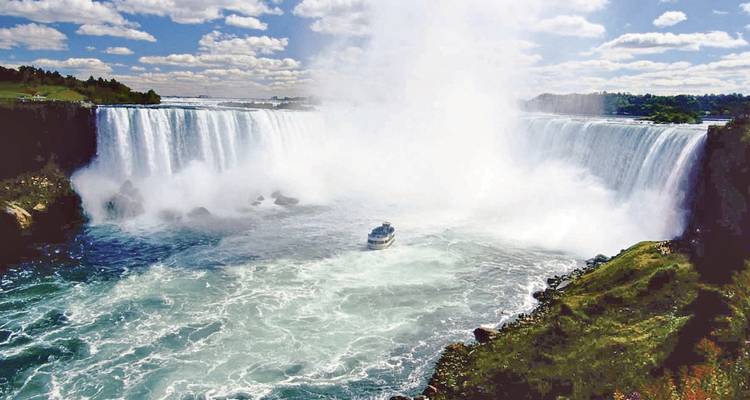 Un plan large des chutes du Niagara avec un bateau près des éclaboussures.