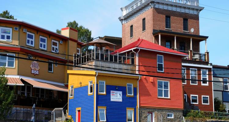 Maisons colorées dans une rue avec un ciel dégagé.