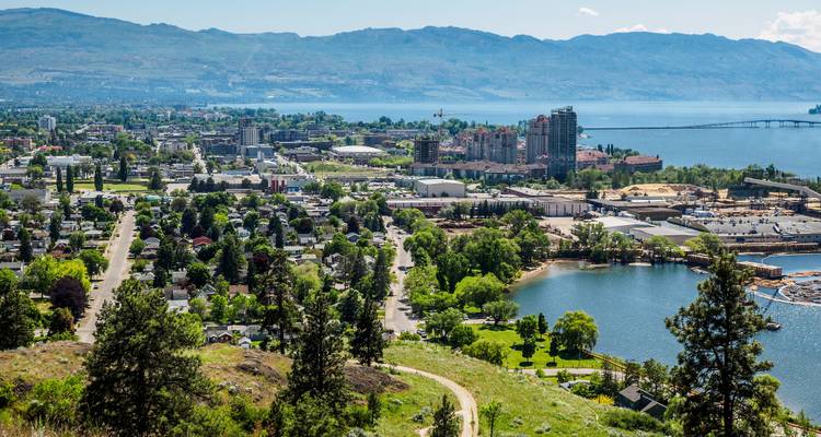 Une vue panoramique d'une ville au bord d'un lac avec des montagnes en arrière-plan.