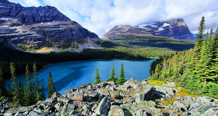 Un lac bleu cristallin entouré de montagnes escarpées et de forêts.