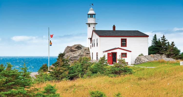 Phare sur une falaise surplombant l'océan avec un ciel dégagé.