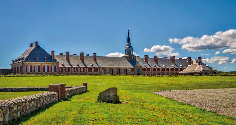 Forteresse historique avec un grand champ d'herbe et un ciel bleu.