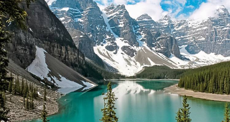 Lac turquoise avec des montagnes enneigées en arrière-plan.