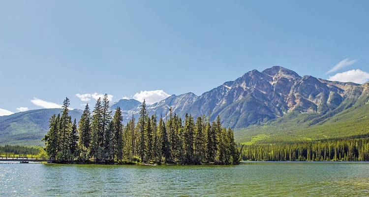 Rustig meer omringd door dennenbomen en bergen.