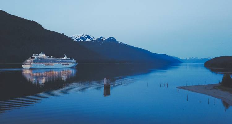 Cruiseschip dat tijdens de schemering door een fjord vaart.