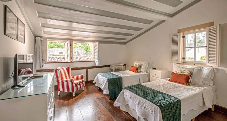 Intérieur d'une chambre d'hôtel avec deux lits et une vue sur les arbres.