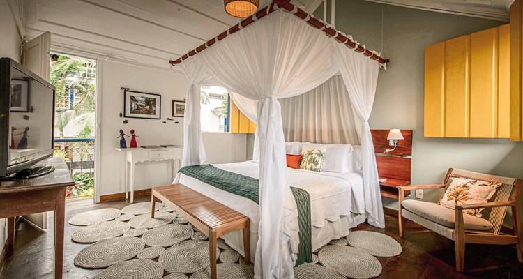 Chambre élégante avec un grand lit sous un baldaquin, décorée d'art et de meubles.