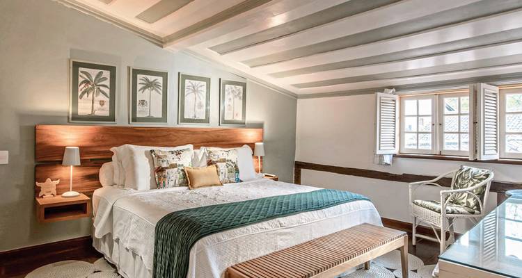 Chambre confortable avec un grand lit sous un plafond mansardé, décorée avec de l'art et des meubles.