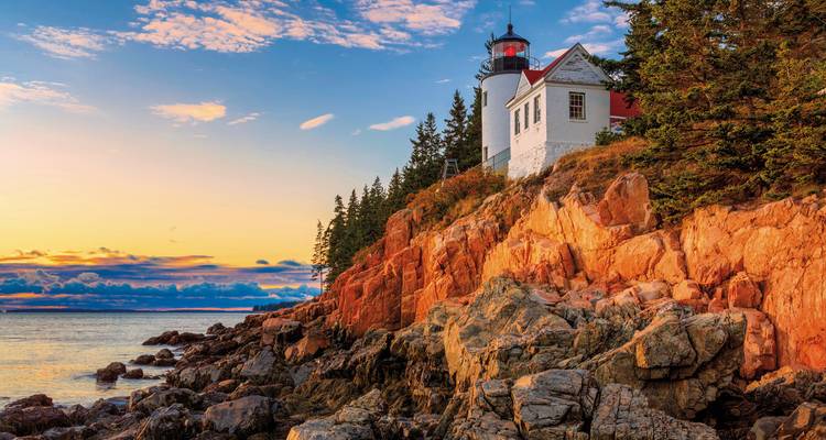 Phare emblématique perché sur des falaises rocheuses aux teintes rouges au coucher du soleil le long de la côte du Maine.