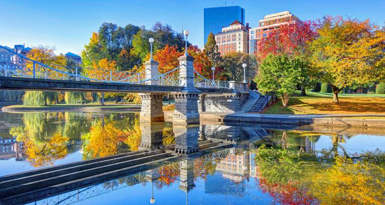 Un élégant pont en fonte et le feuillage automnal se reflètent parfaitement dans le calme étang du Boston Public Garden.