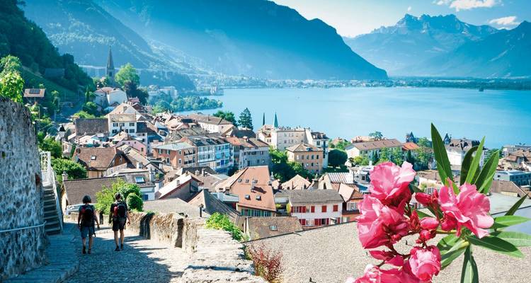 Lakeside town with hikers and pink flowers.