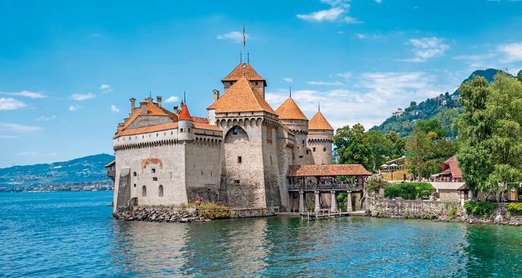 Chateau on a lake with mountain backdrop.