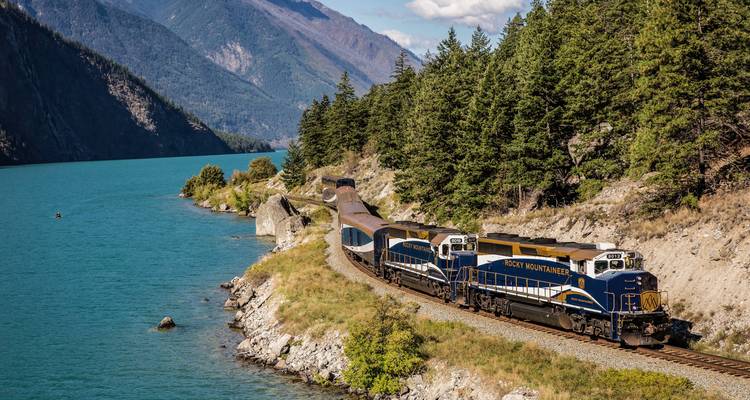Train voyageant le long d'un lac bleu turquoise.